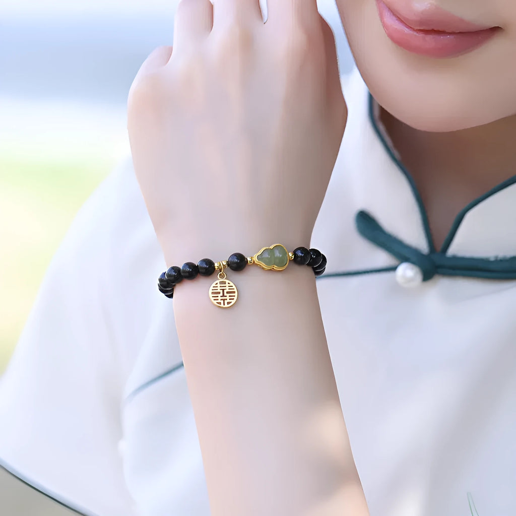 Black obsidian bracelet with a Hetian jade gourd pendant, showing geometric beads.