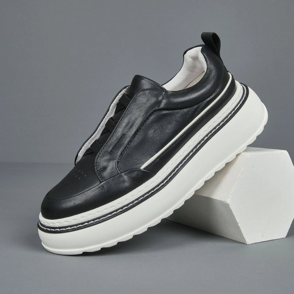 Black casual slip-on sneaker with leather upper, foam platform sole, and elastic band – side view