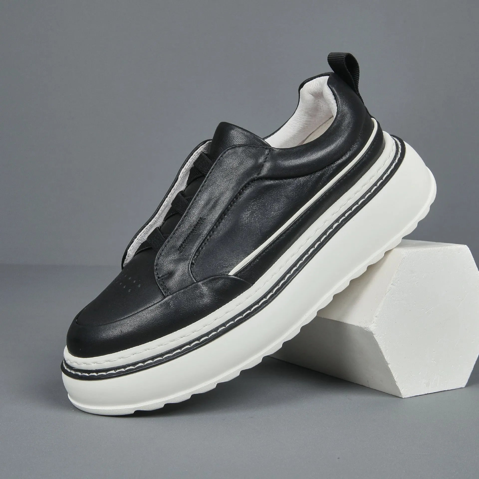 Black casual slip-on sneaker with leather upper, foam platform sole, and elastic band – side view