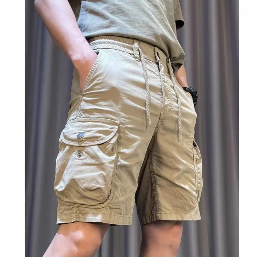 A model wearing loose-fit, straight-leg, multi-pocket overalls trousers in a khaki colour.