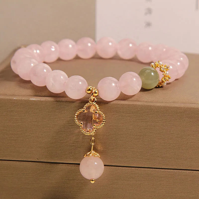 Pink crystal four-leaf clover pendant bracelet for women with rhinestones on alloy band.