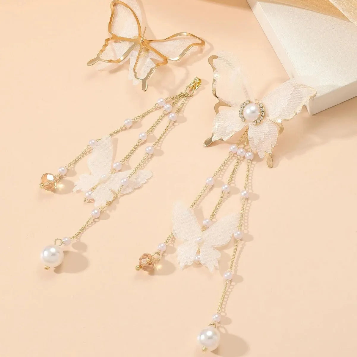 White butterfly-shaped drop earrings with sparkling rhinestone pearls and long white lace tassels.