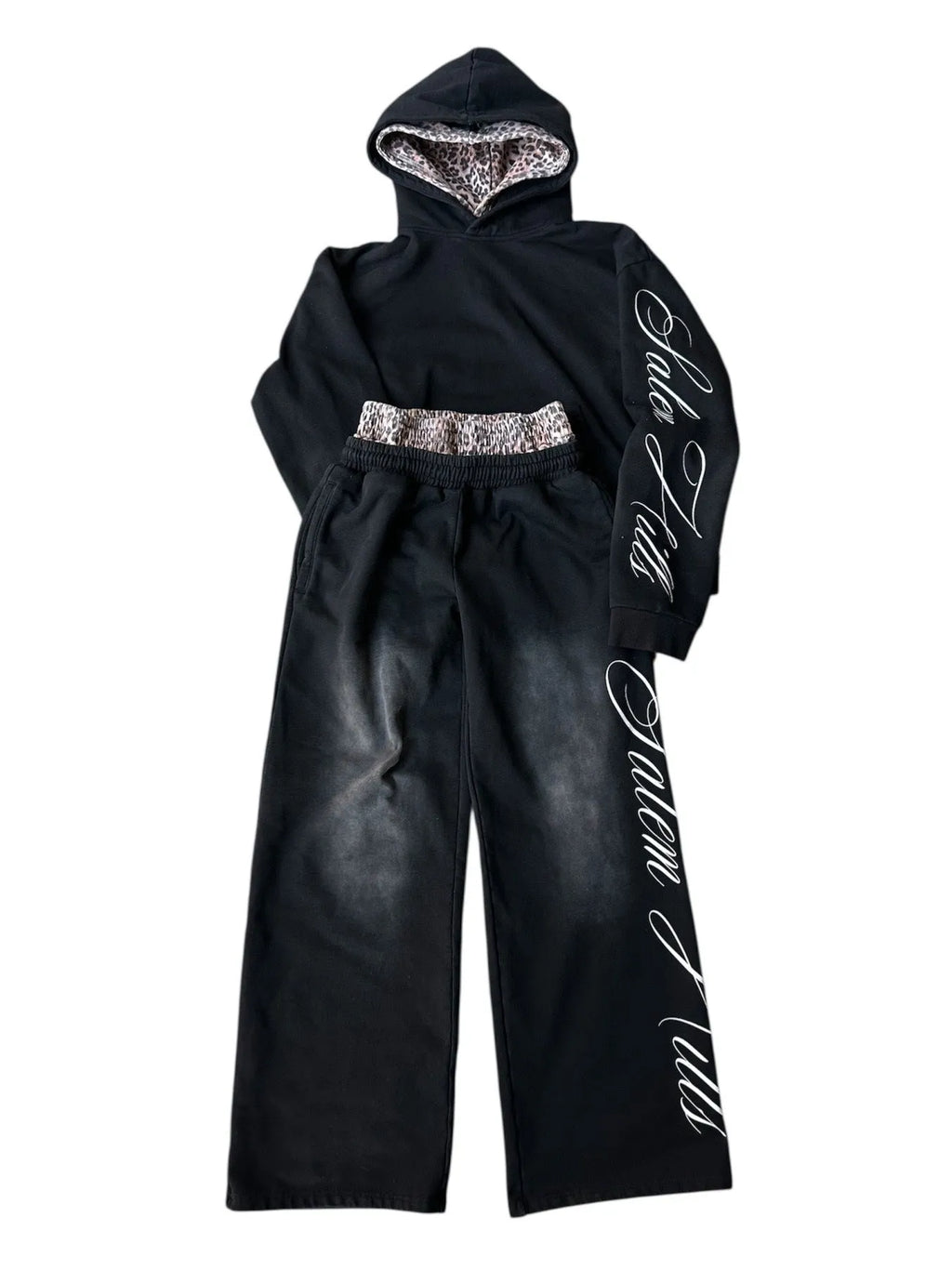 Man wearing a black punk-print hooded pullover jumpsuit with long sleeves and fleece lining.