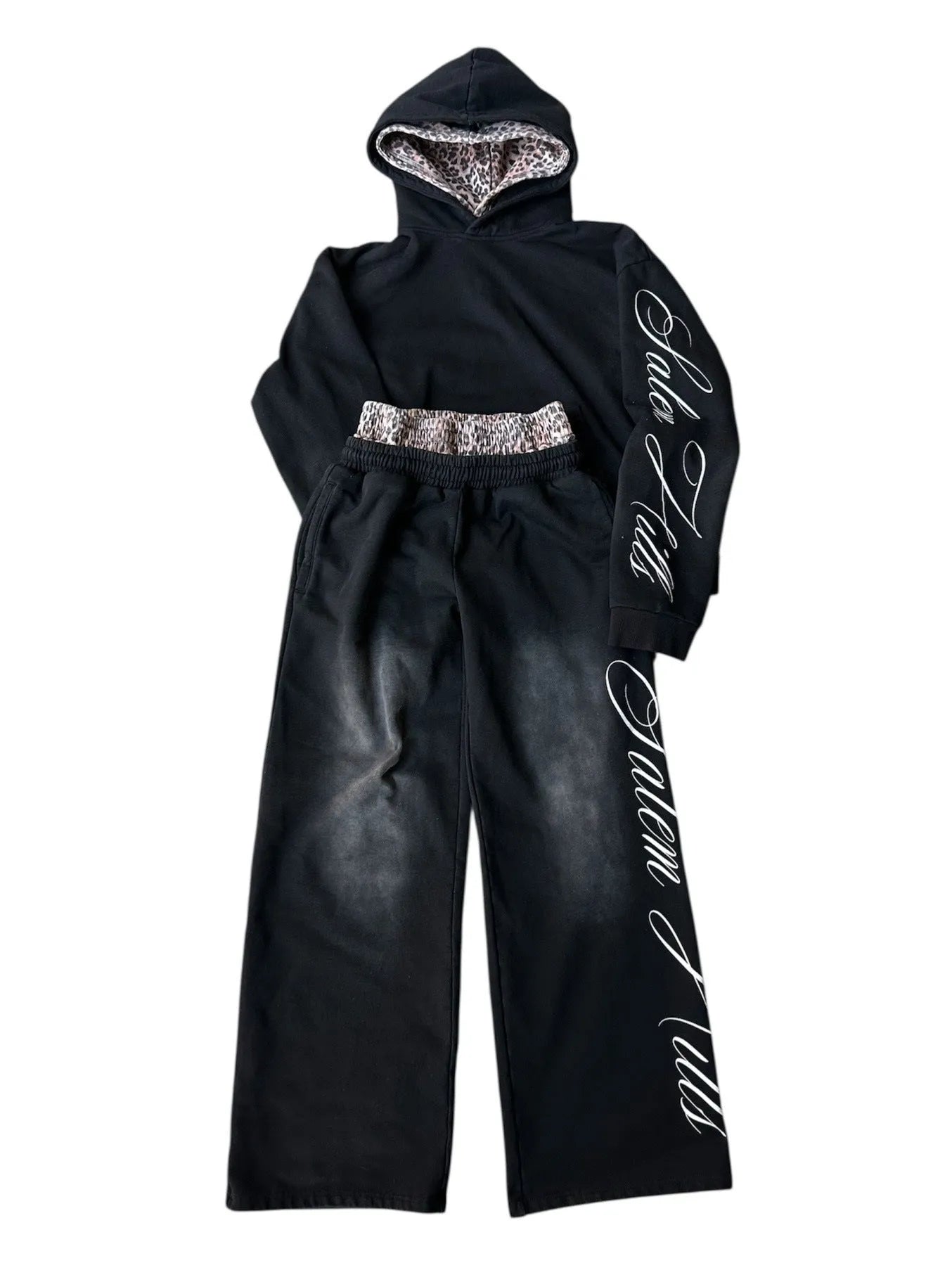 Man wearing a black punk-print hooded pullover jumpsuit with long sleeves and fleece lining.