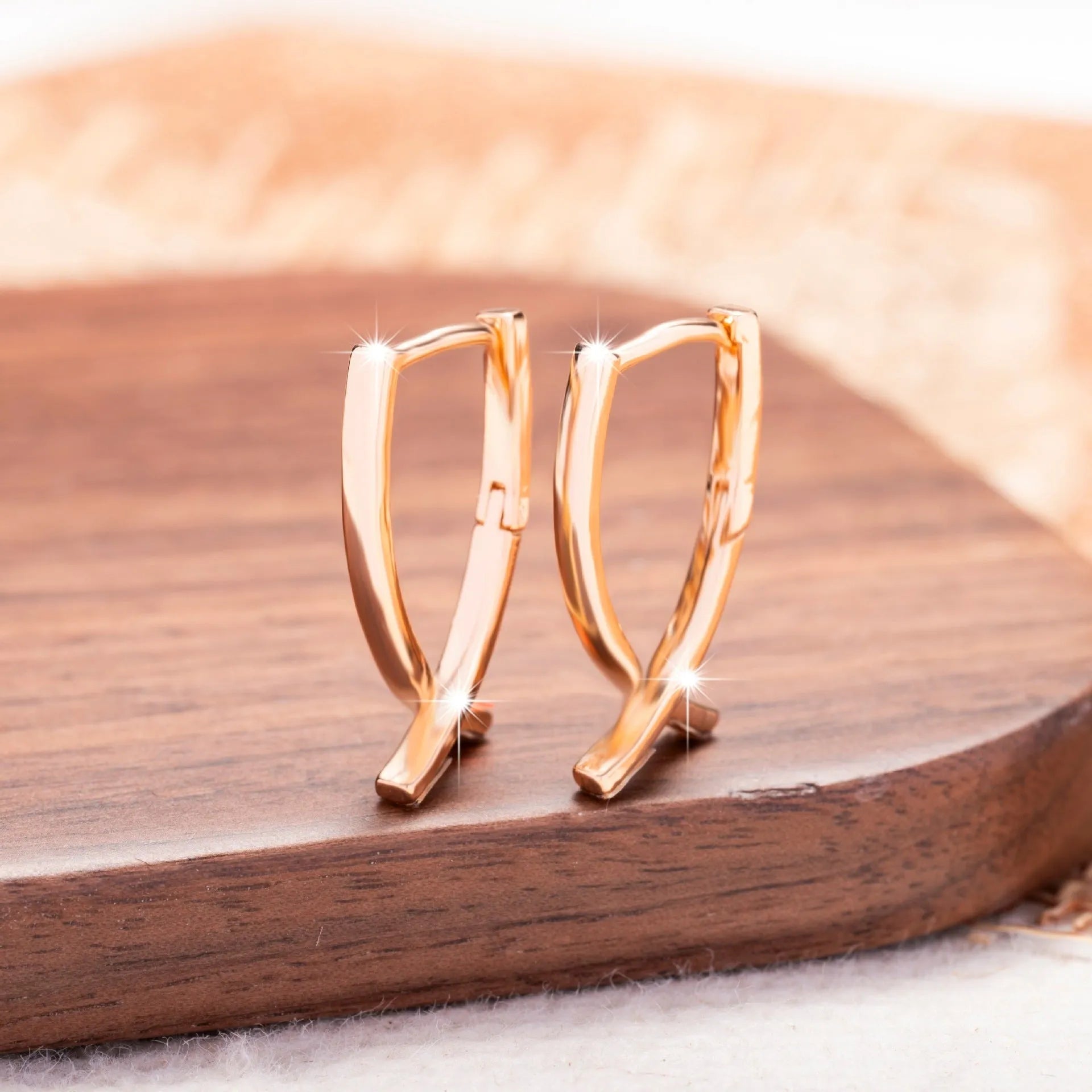 A pair of rose gold coloured cross shaped earrings made from polished copper.