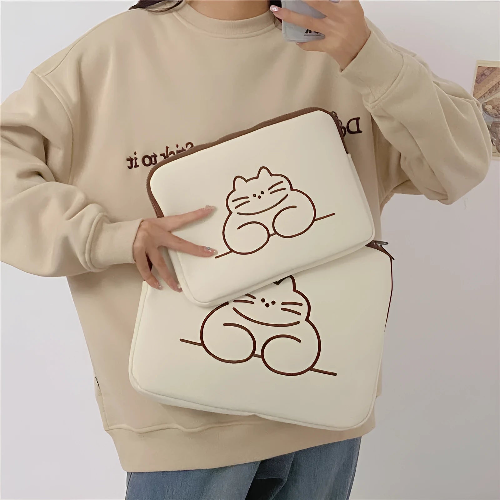 Embroidered fat cat design on a grey nylon laptop protective sleeve with a black zipper.
