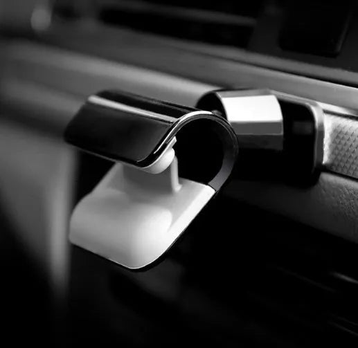 Black 360-degree rotating car phone holder mounted on a car air vent, showing a mobile phone secured in the cradle