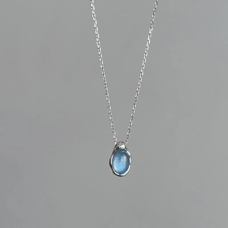 Close-up of a navy blue and platinum coloured geometric water drop pendant necklace on an adjustable copper chain.
