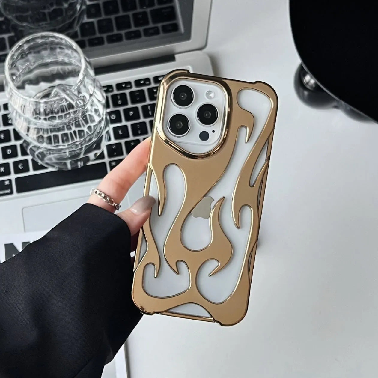 Electroplated hollow flame pattern soft TPU phone case for Apple iPhone on a table.