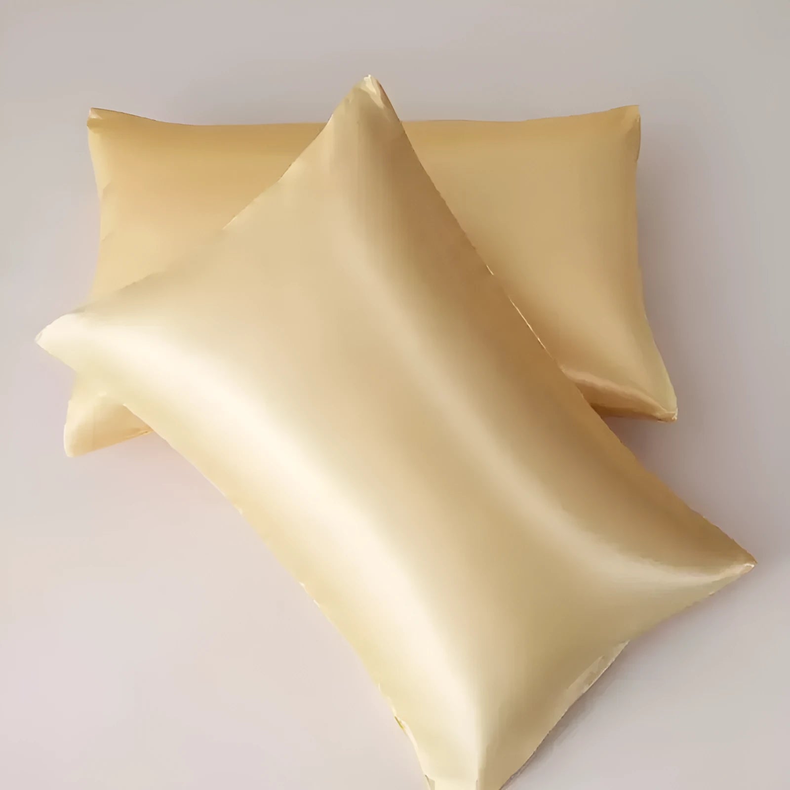 A pair of solid colour satin pillowcases made from polyester fabric, showing available size and colour options.