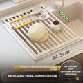 Foldable milky white stainless steel kitchen draining rack shown next to a sink.