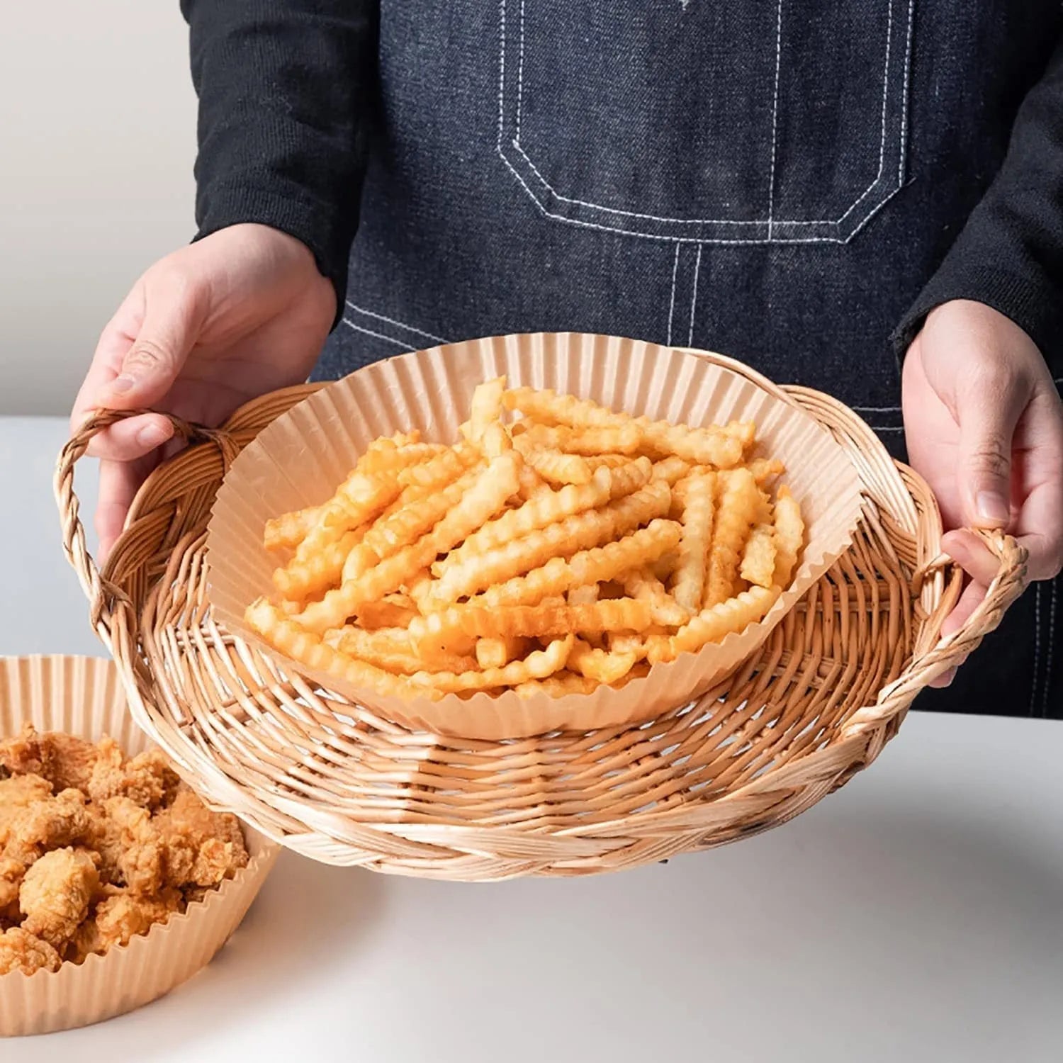 Round white disposable parchment paper liner for air fryer basket with raised edges.