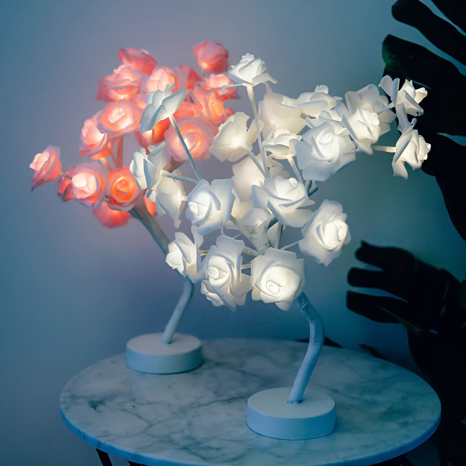 White and red rose shaped LED table lamp with bonsai tree base on a wooden table.