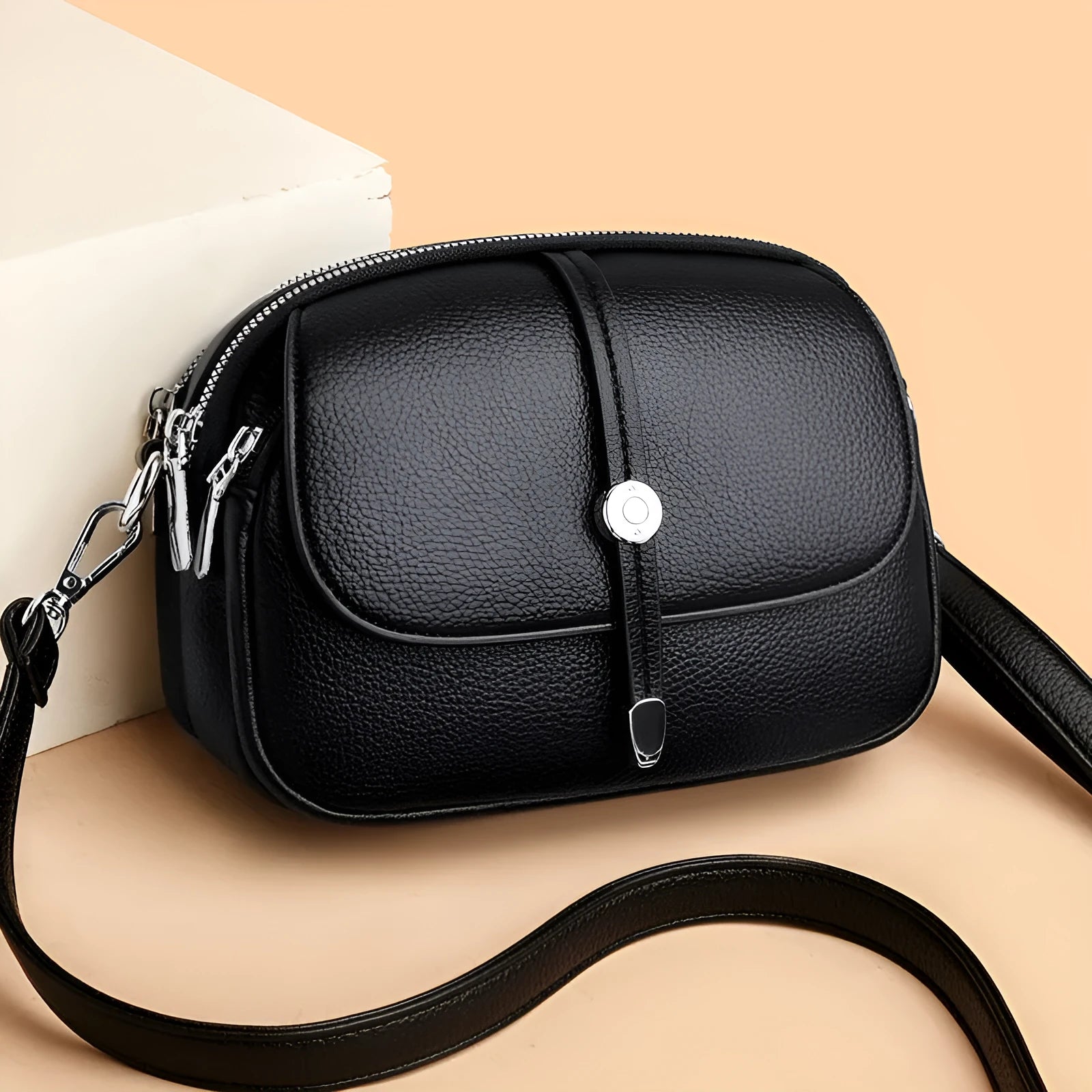 Soft black oval crossbody shoulder bag for women with visible stitching and a shoulder strap.
