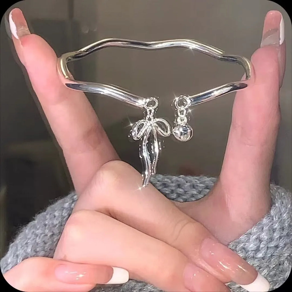 Silver adjustable bracelet with a bow charm and bell opening clasp