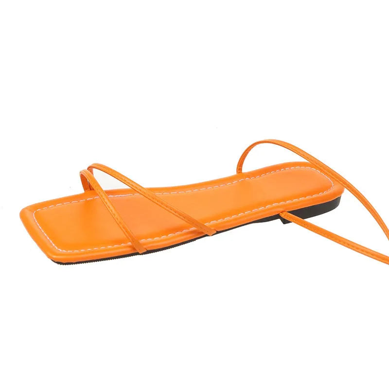 Women's flat sandals with an ankle ring bandage cloth strap and front lace-up fastening in orange.