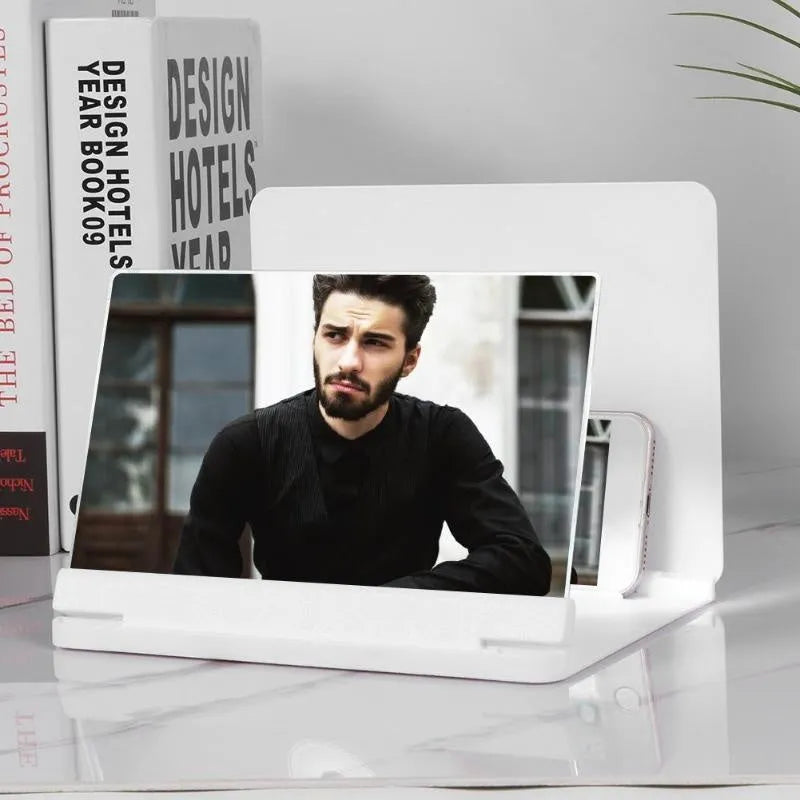 White and black smartphone screen magnifier with integrated phone holder on a table.