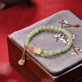 Hand-strung jade bracelet with a gold gourd charm and fu character charm.