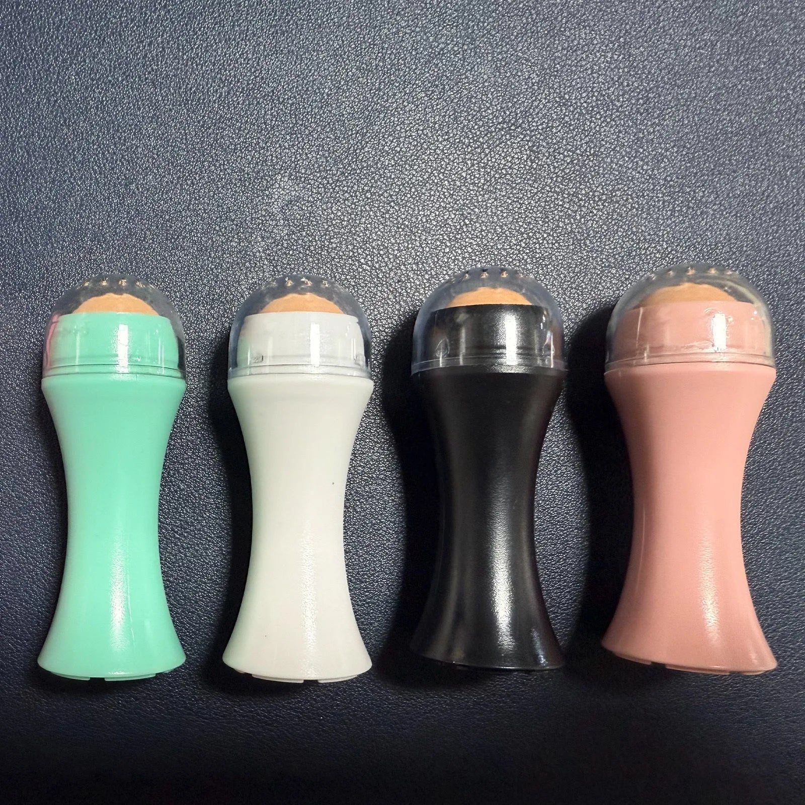 Volcanic stone portable reusable face roller for oily skin control in black, green, pink, or white.