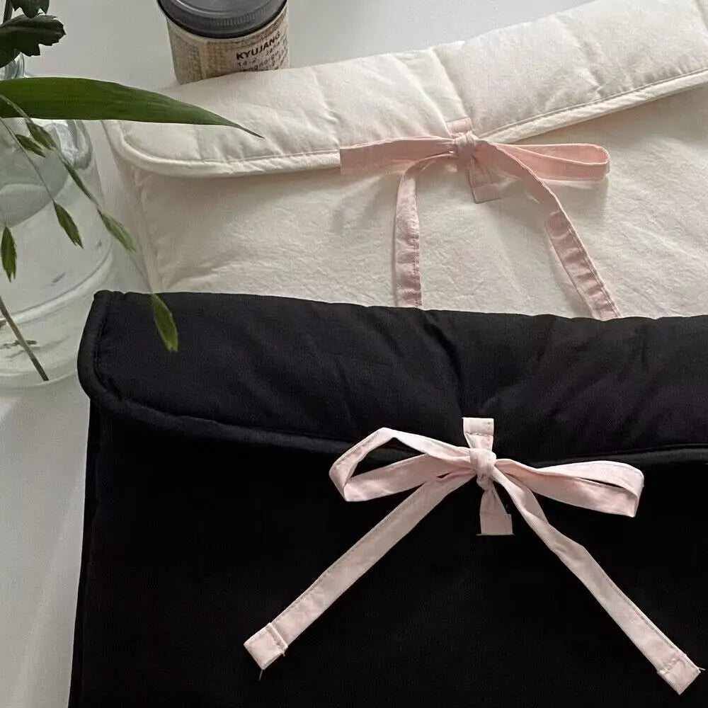 Women's black and white quilted ballet style laptop bag with bow, shown in two sizes.