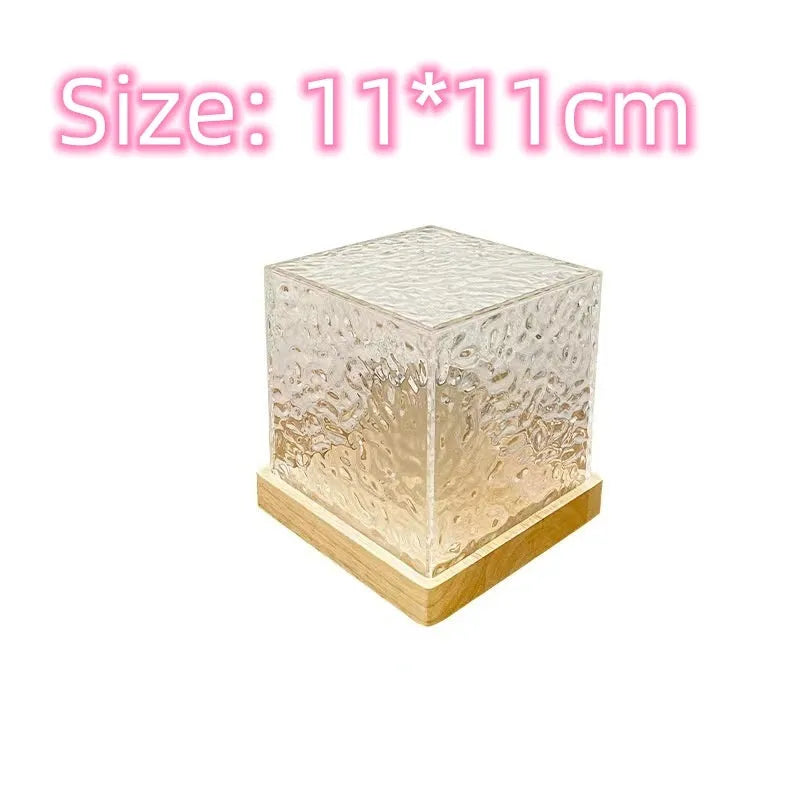 Modern geometric crystal table lamp projecting colourful water ripple light effect on wall.