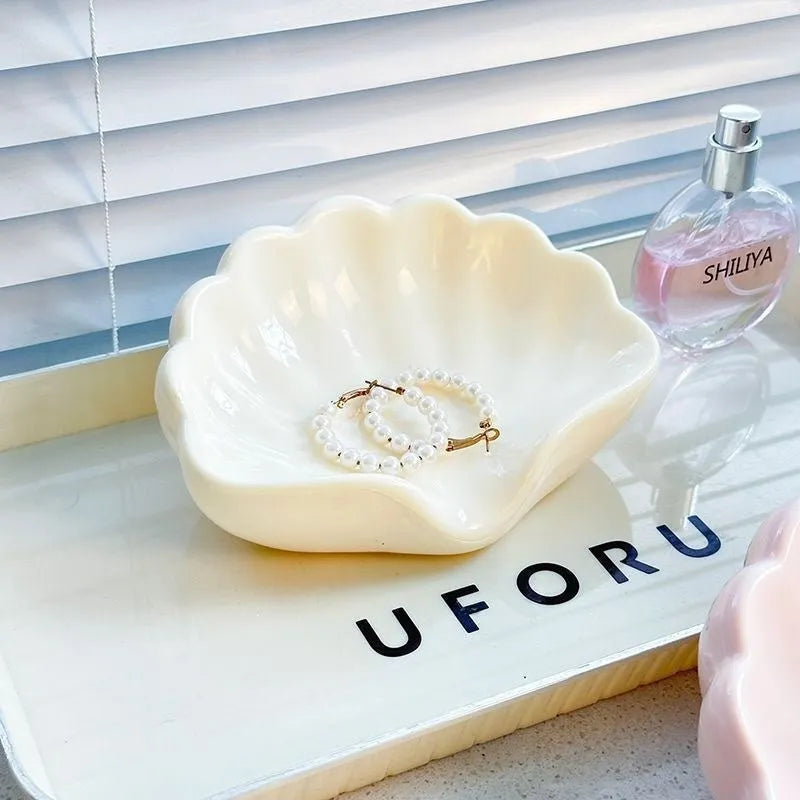 White or pink plastic shell-shaped soap dish for bathroom countertop or shower storage.