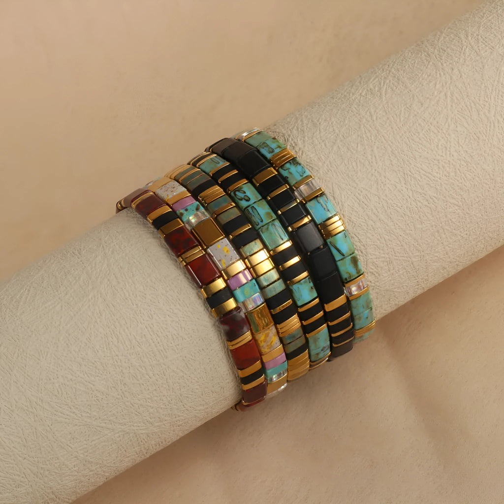 Geometric beaded bracelet with round elements in milky white, black, green, blue, or red.