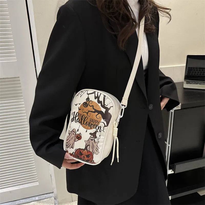 Black Halloween crossbody bag with graffiti print of cartoon pumpkins, ghosts, and bats.