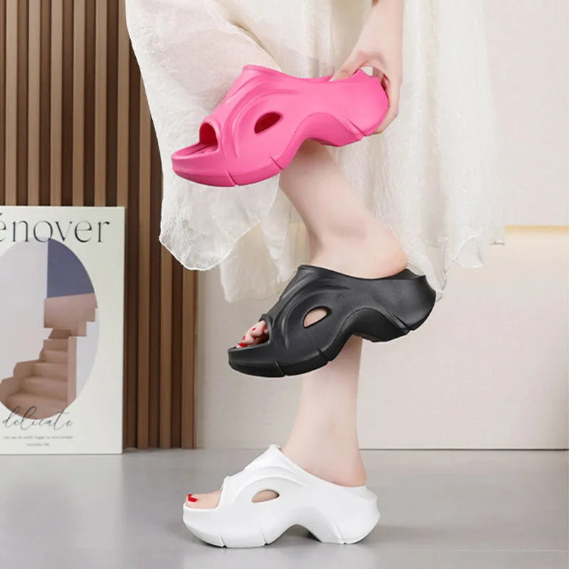 Women's white thick-soled EVA foam slippers with rounded toe on a beach.