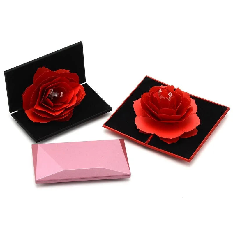 Red heart-shaped plastic ring box on a white background, showing its rotating mechanism.