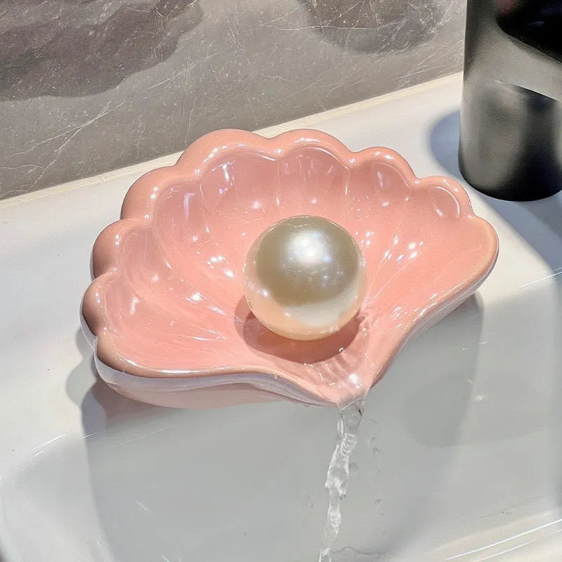 White or pink plastic shell-shaped soap dish for bathroom countertop or shower storage.