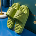 A pair of solid-colour EVA bathroom slippers with a thick, textured sole, shown on a bathroom floor.