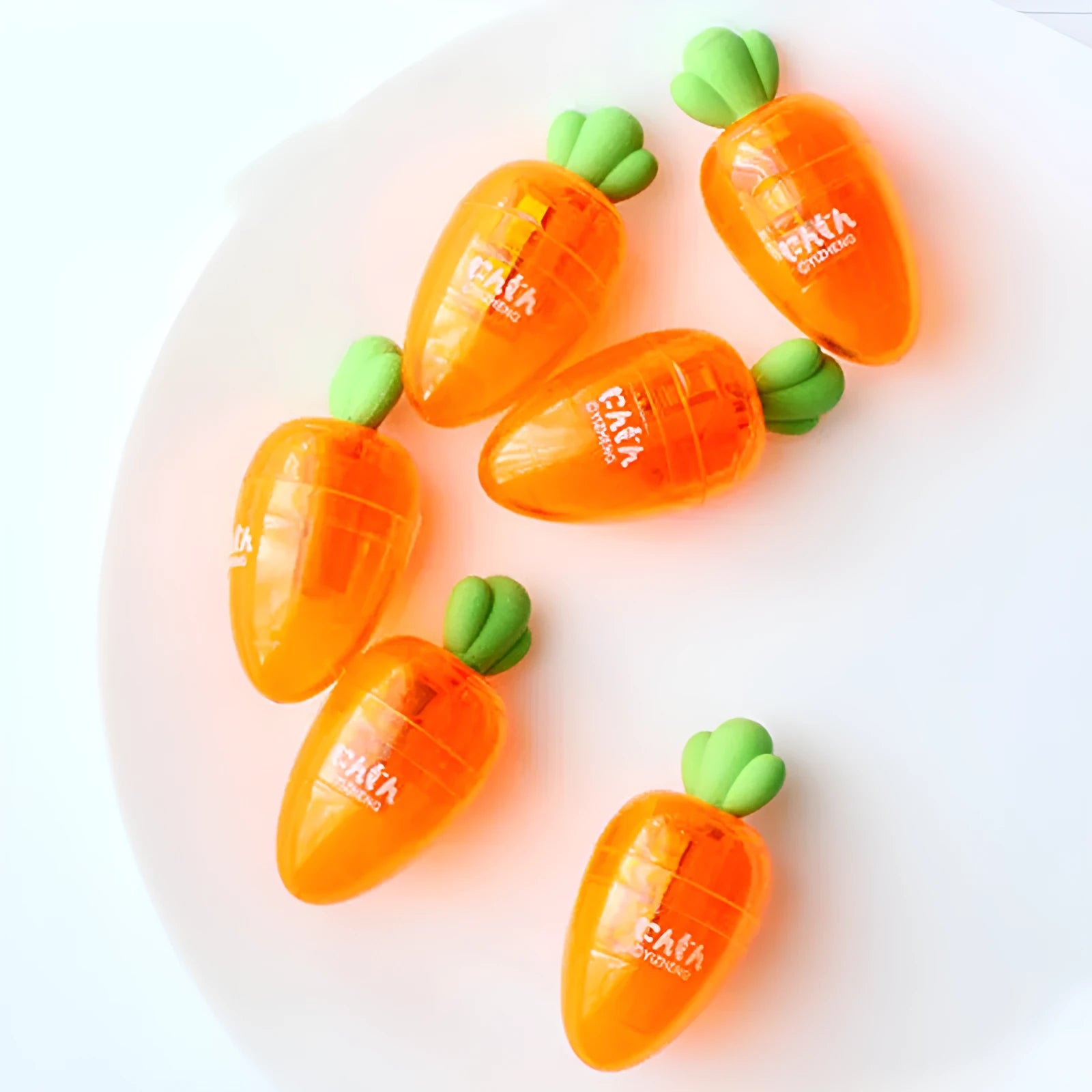 Carrot-shaped plastic manual pencil sharpener with extended handle on a white background.