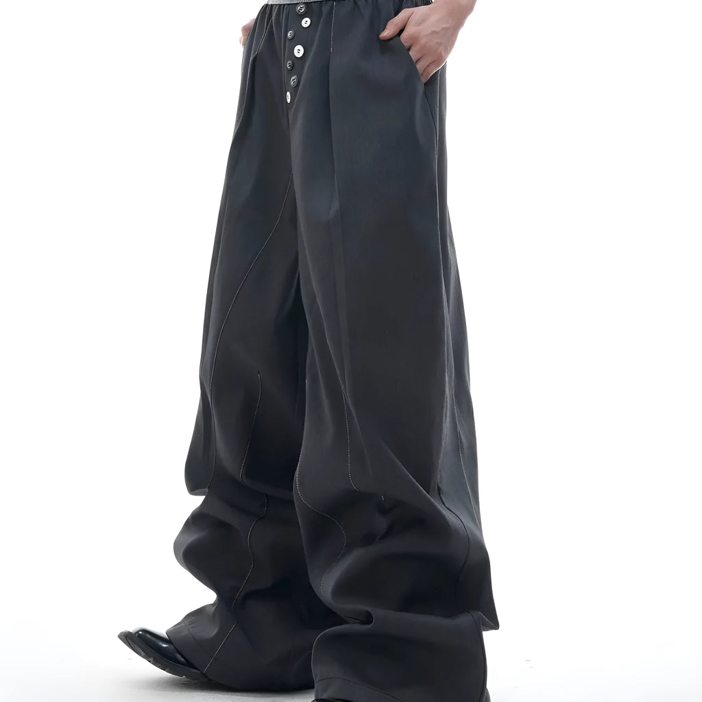 Men's black drooping straight-leg suit trousers with high waist and button detail.