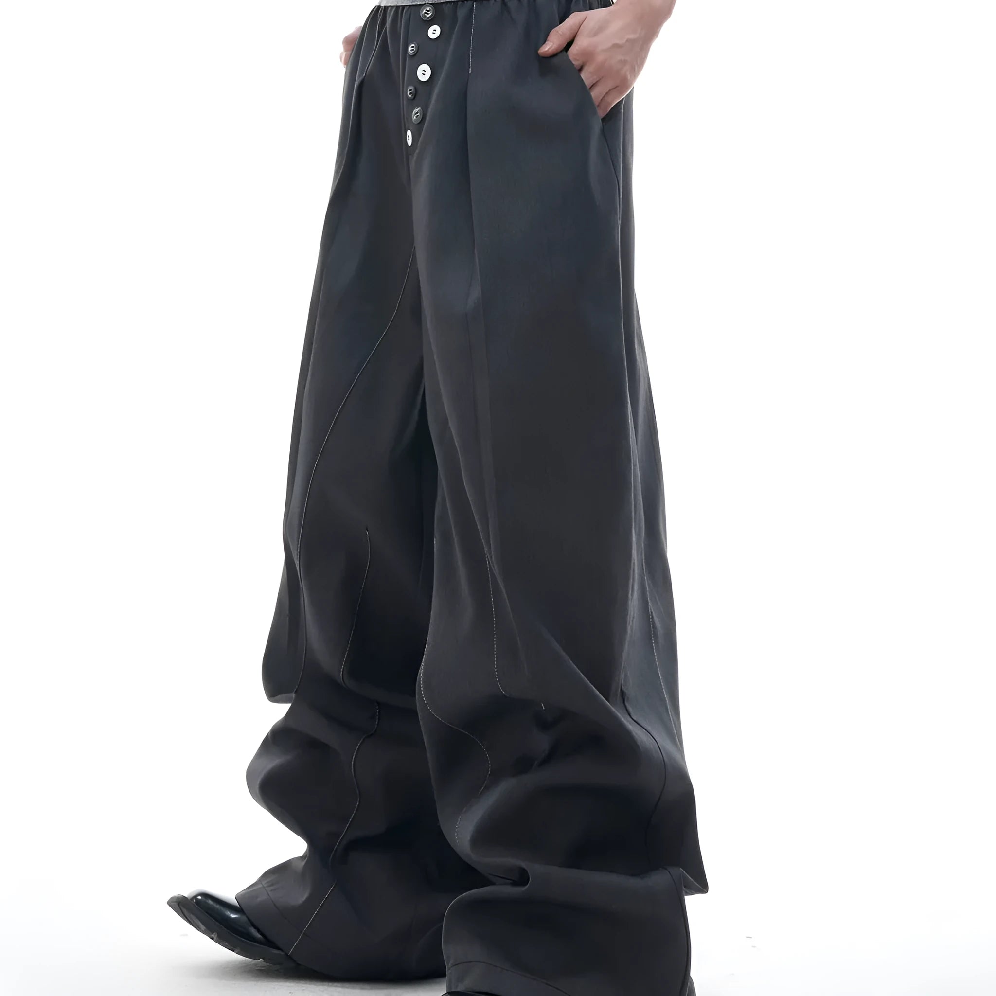 Men's black drooping straight-leg suit trousers with high waist and button detail.