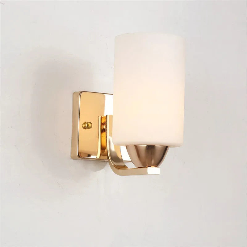 Chrome-plated wall lamp with clear glass shade mounted beside bed
