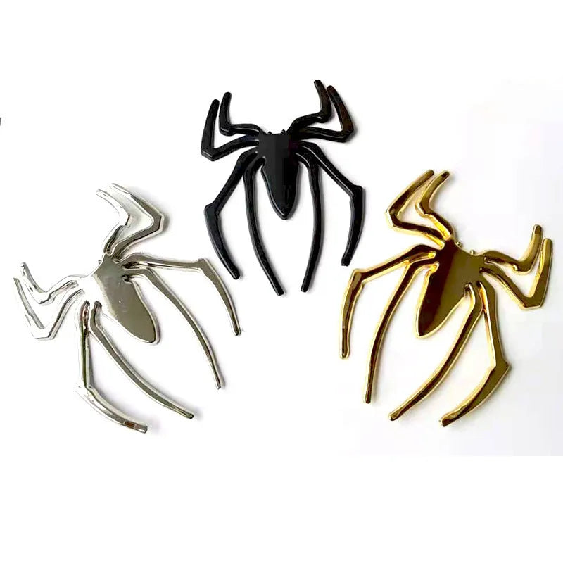 Three-dimensional metal spider bumper sticker in zinc alloy, shown in gold colour, measuring 7 by 5 cm.