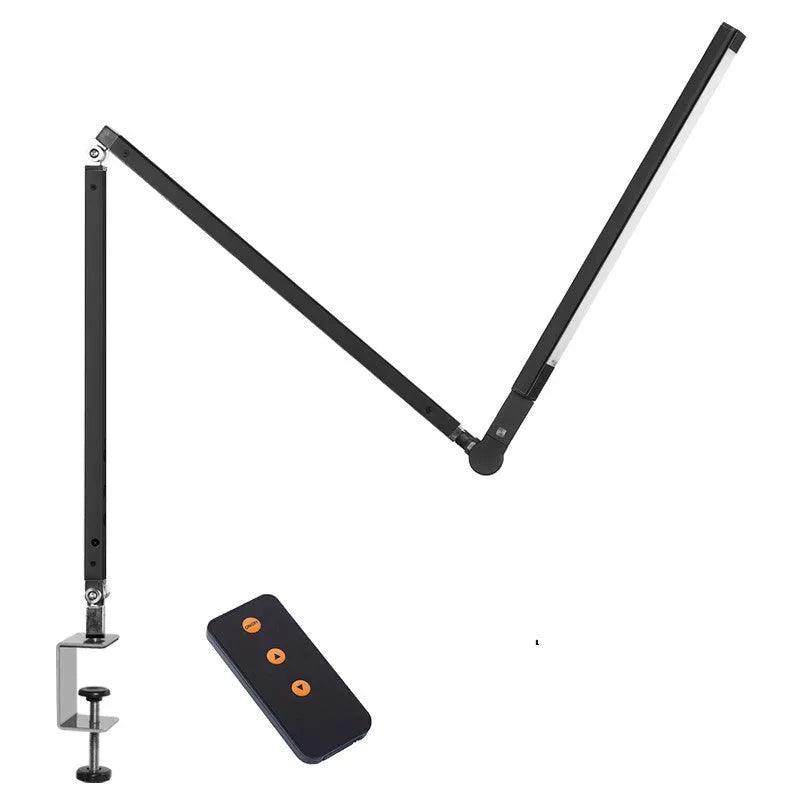 Aluminium clip-on desk lamp with adjustable arm and remote control on a wooden desk.