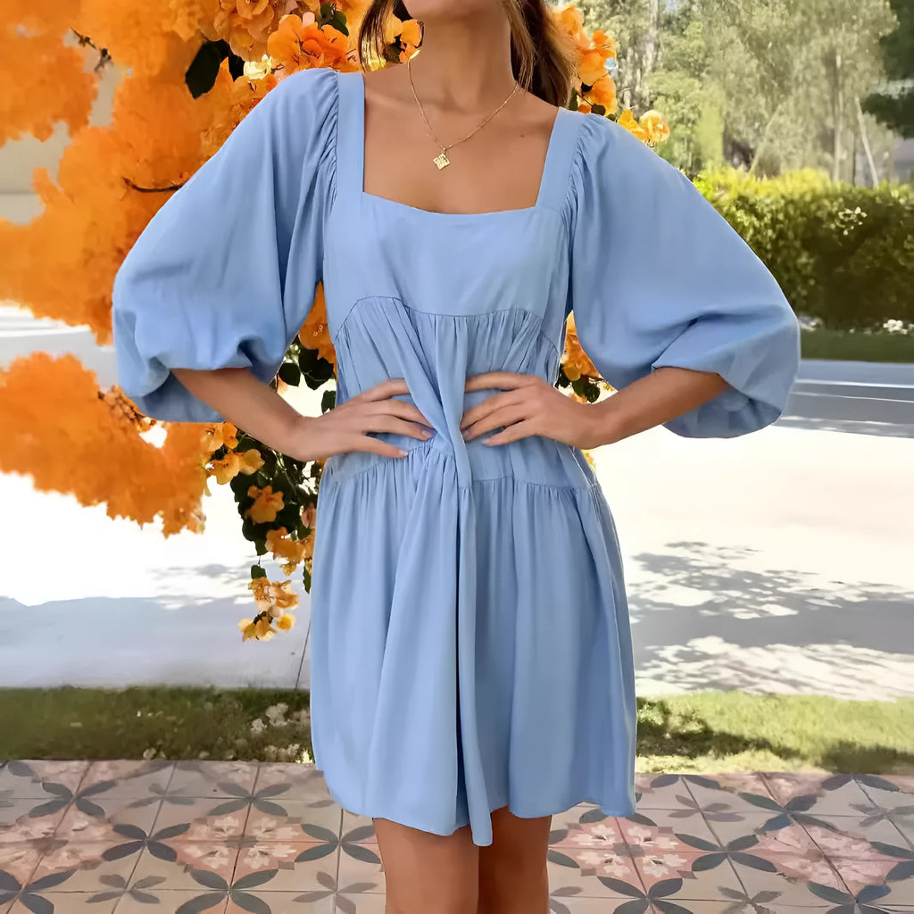 Orange red children's backless dress with square collar and puff sleeves on a mannequin.