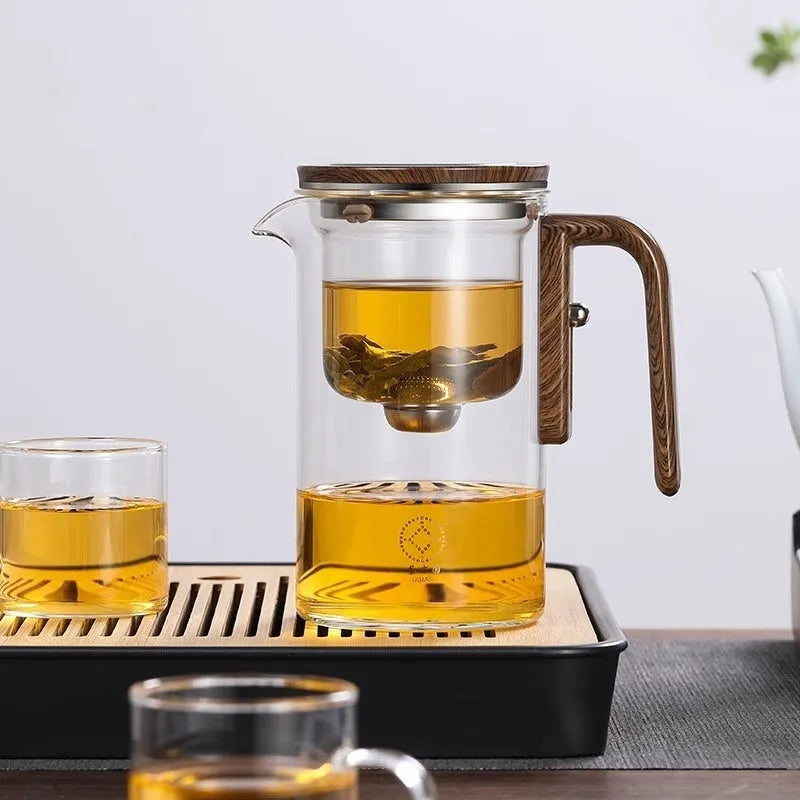 Glass teapot with wooden handle showing magnetic separation mechanism for loose leaf tea brewing