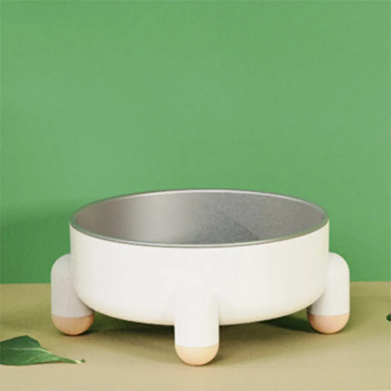 Green stainless steel pet bowl with non-slip base and high foot on a kitchen floor.