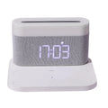 White bedside table lamp with integrated digital clock and wireless phone charging pad on base.