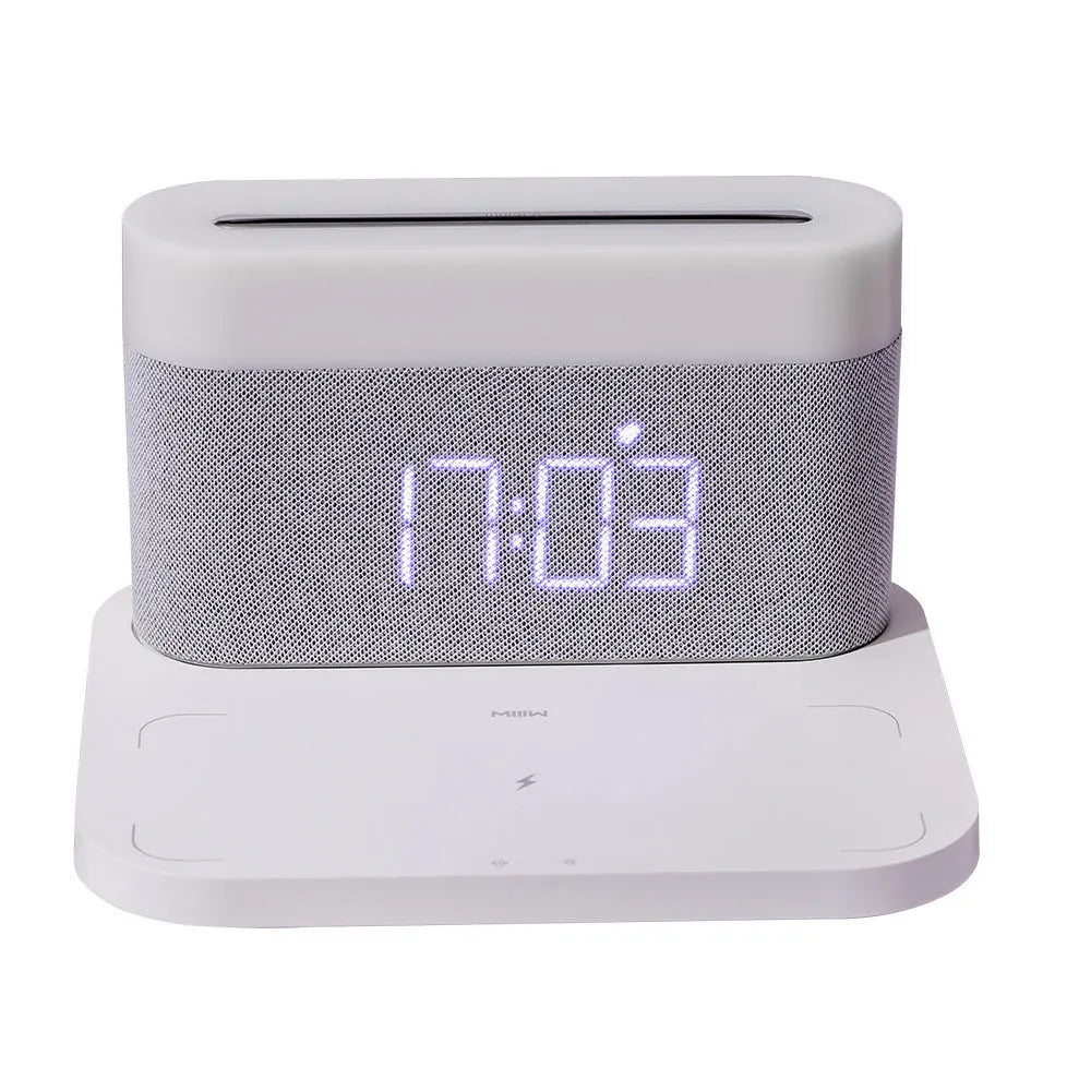 White bedside table lamp with integrated digital clock and wireless phone charging pad on base.