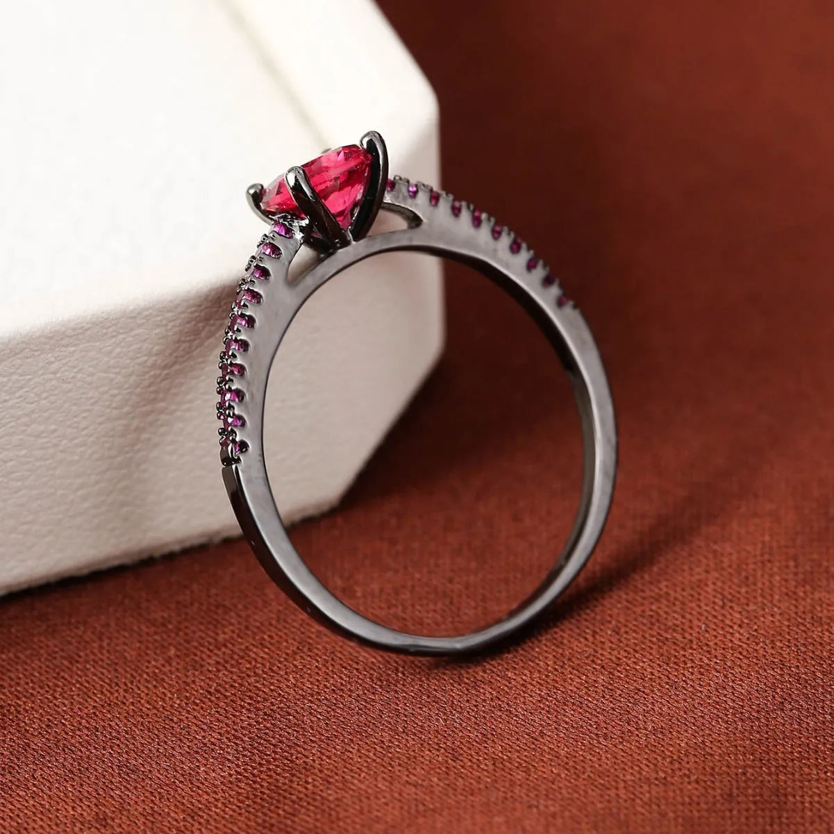 Geometric hexagonal copper ring with colourful zircon stones on a grey background.