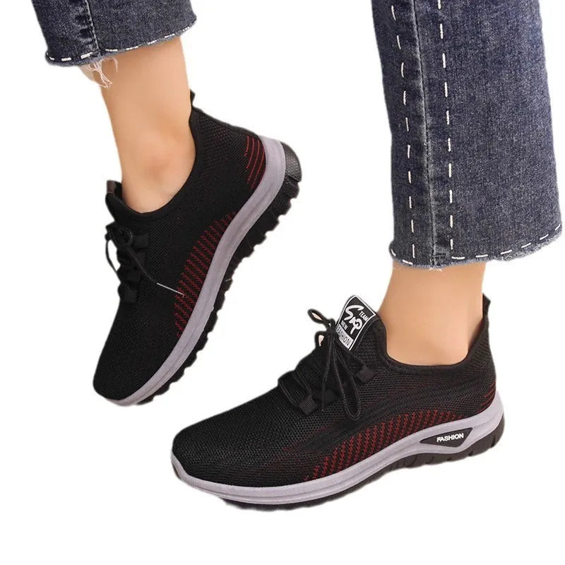 Women's low top sneakers in black with mesh panels, cross straps, and a round toe head on a rubber sole.