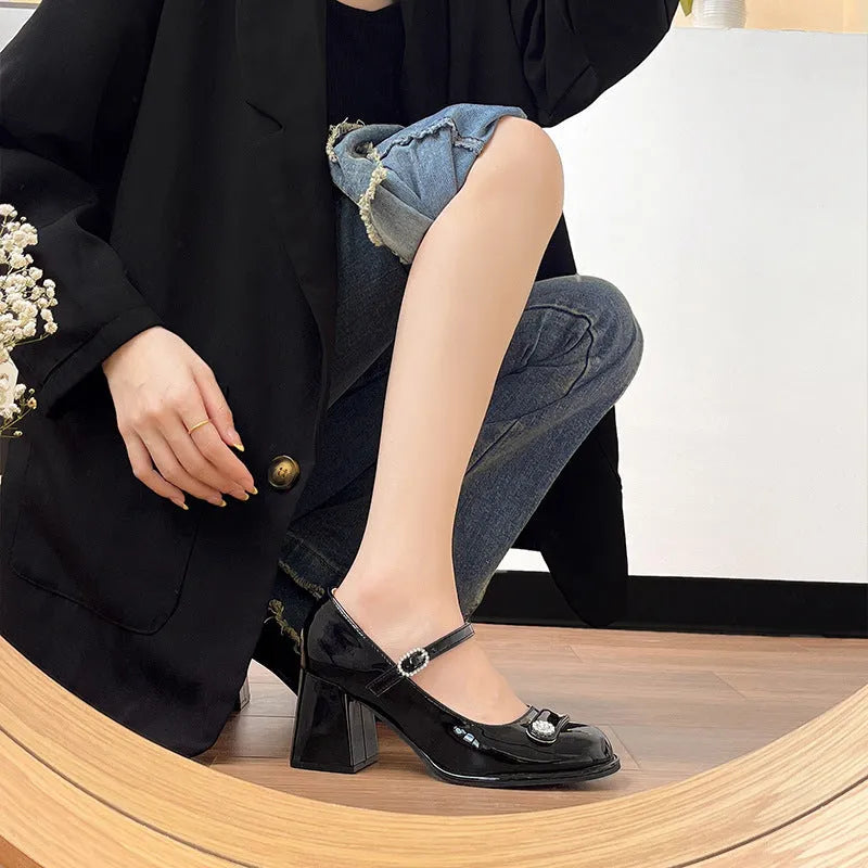 Women's black patent leather round toe shoes with a chunky block heel and buckle fastening.