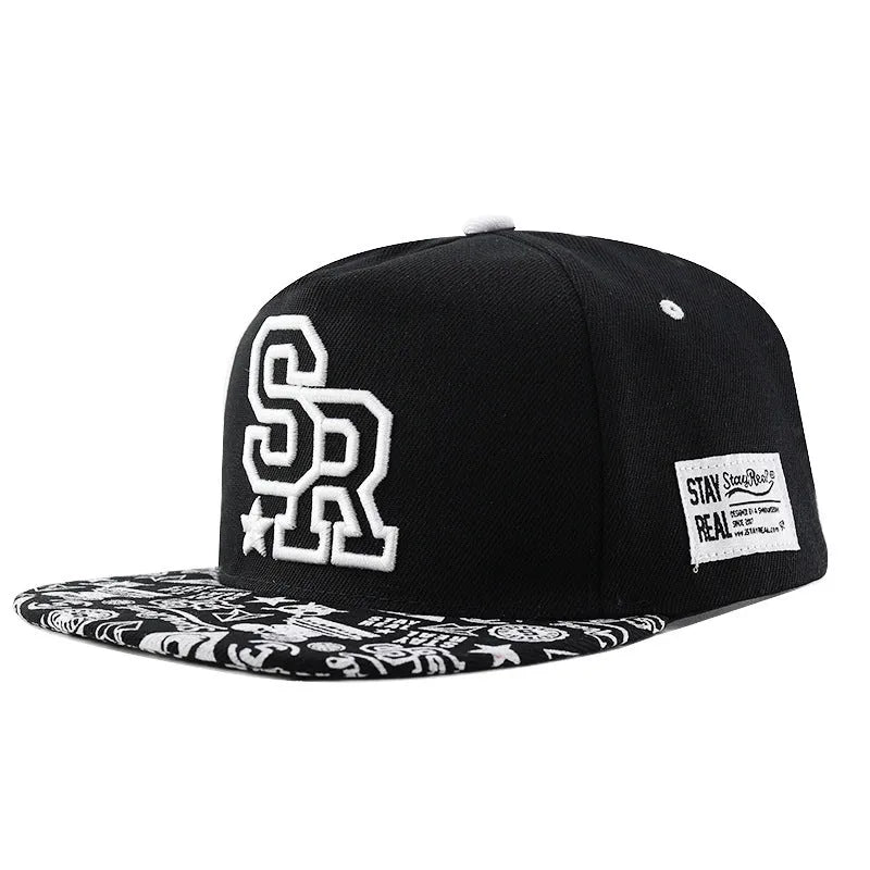 Black cotton baseball cap with white letter embroidery on the front, showing adjustable strap.