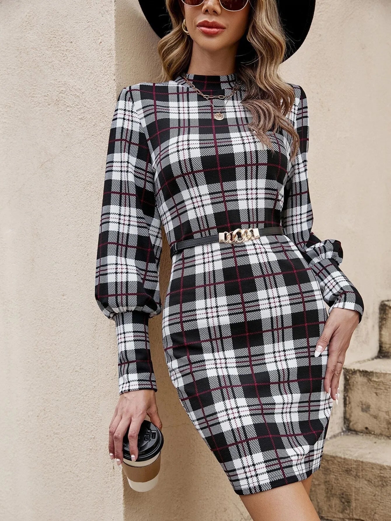 A black tight-fitting dress with lantern sleeves and decorative leather stitching, modelled on a mannequin.