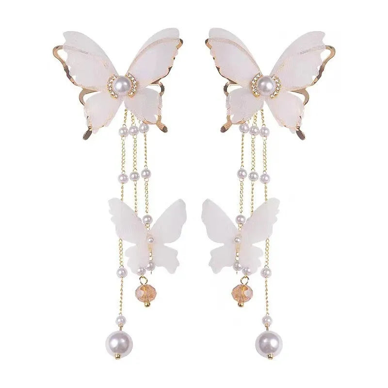 White butterfly-shaped drop earrings with sparkling rhinestone pearls and long white lace tassels.