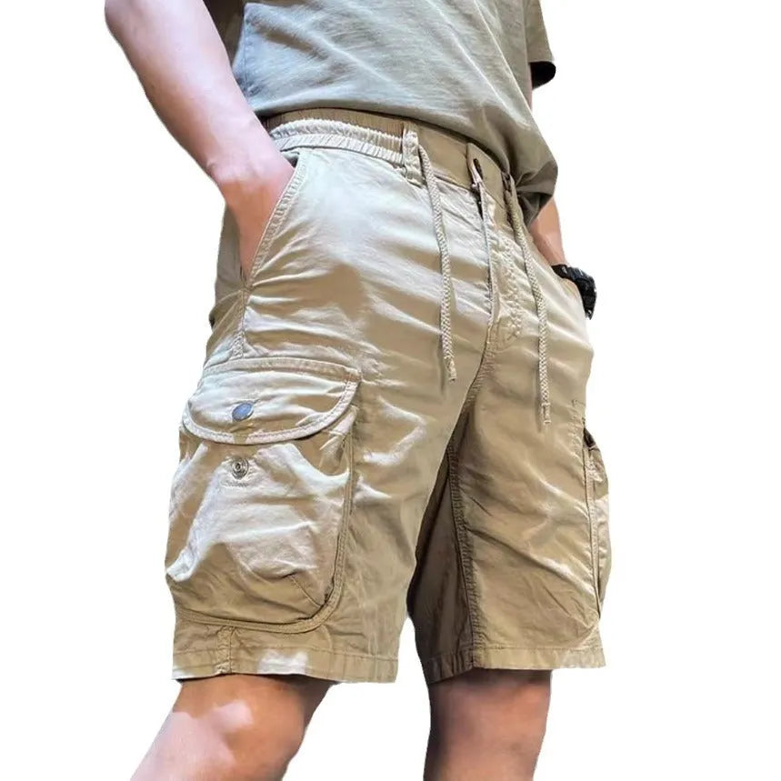 A model wearing loose-fit, straight-leg, multi-pocket overalls trousers in a khaki colour.